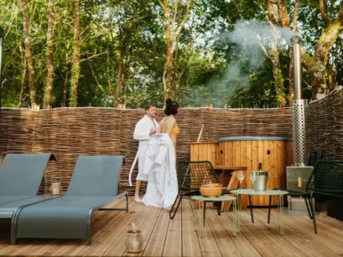 Couple en peignoir près du bain nordique fumant du Lodge Miroir, spa privatif en Vendée