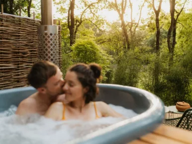 Couple complice dans le jacuzzi fumant du Lodge Miroir, spa privatif en Vendée