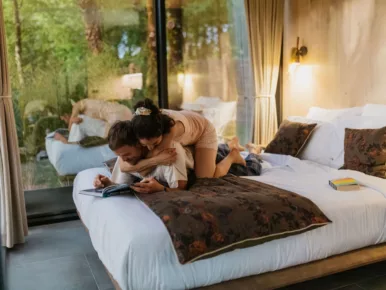 Couple détendu sur le lit face à la forêt au Lodge Miroir, nuit insolite en Vendée