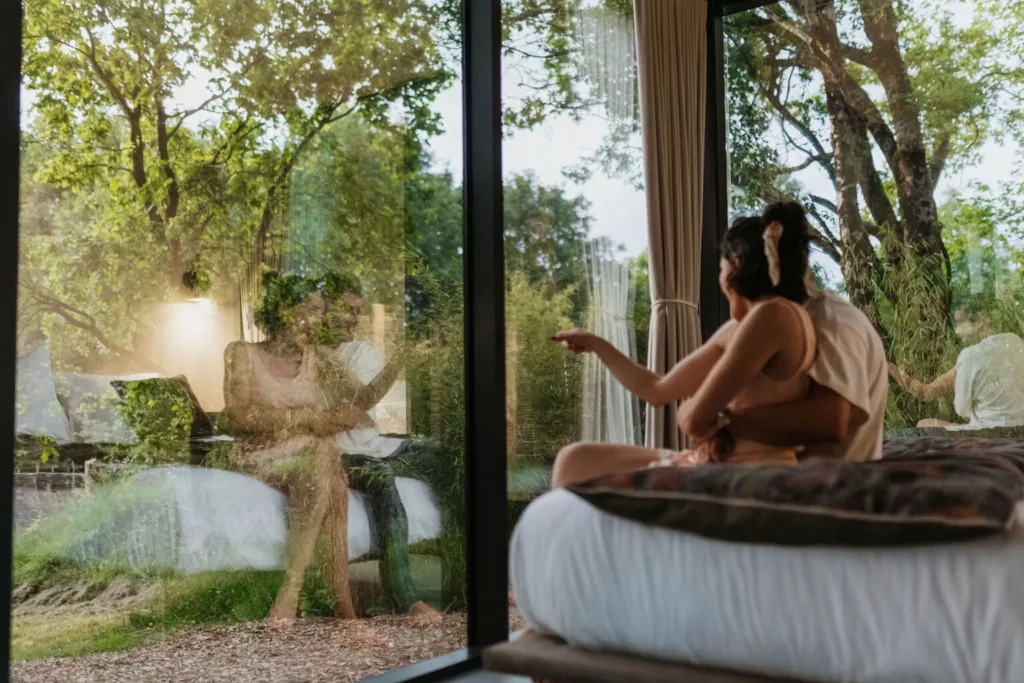 Couple contemplant la forêt depuis la chambre du Lodge Miroir, séjour insolite en Vendée