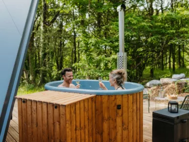 Couple dans le bain nordique au poêle à bois face à la forêt en Vendée