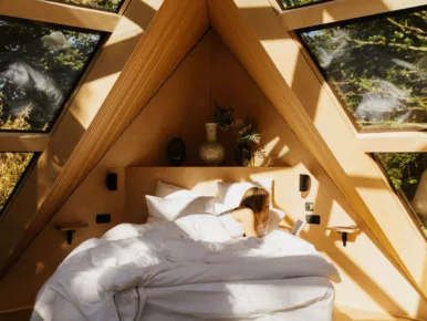 Lecture au lit sous les baies triangulaires du Lodge Étoile en Vendée