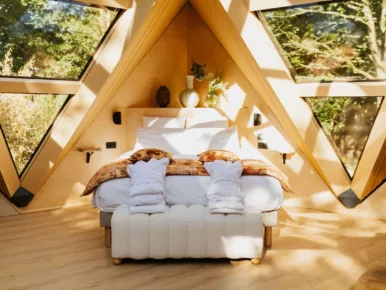 Chambre du Lodge Étoile avec lit face aux baies vitrées sur la nature
