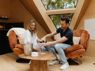Couple trinquant au champagne dans le salon cosy du Lodge Étoile