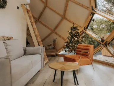 Hébergement insolite avec grande baie vitrée en forme de losange pour couple avec mezzanine décoré avec un sapin pour Noël